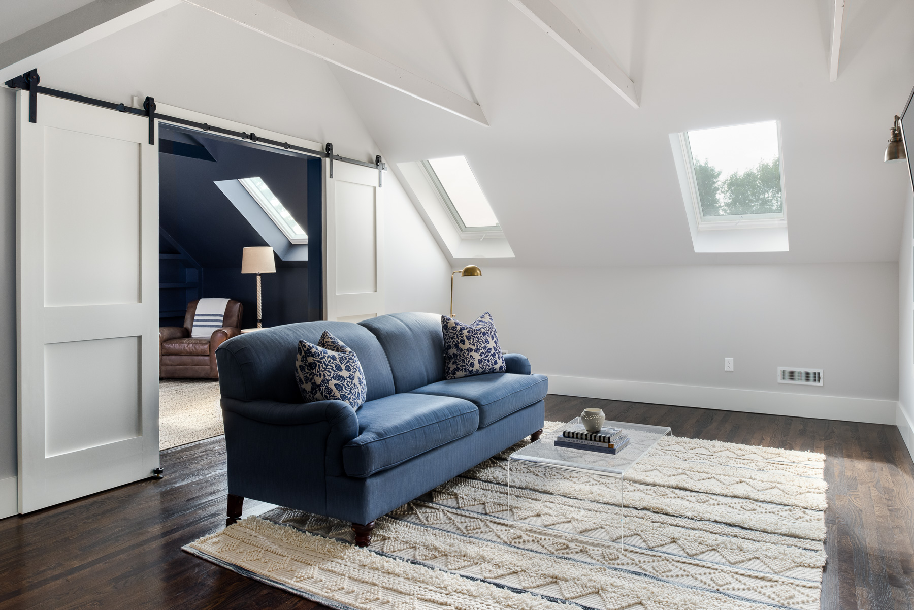 Attic guest lounge with blue sofa and skylights